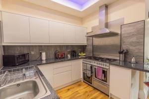 爱丁堡New 3-Bedroom Apartment Close to City Centre的厨房配有白色橱柜和水槽