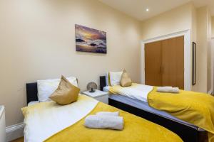 爱丁堡New 3-Bedroom Apartment Close to City Centre的配有黄色床单的客房内的两张床