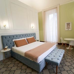 卡塔尼亚Toscano Palace Luxury Rooms Catania的一间卧室配有一张大床和一张桌子及椅子