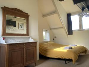 AxelLandhuis 'De Ontspanning'的一间卧室配有一张床、梳妆台和镜子
