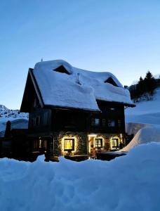 苏特廖Zoncolan Laugiane的雪覆盖着灯光的房子