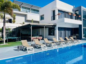 阿德耶Casa Flamboyant With Sea Views & Heated Pool的一个带椅子的游泳池以及一座房子