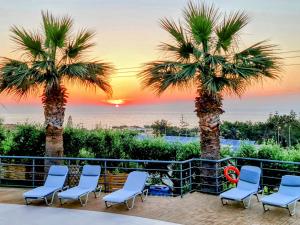 斯加雷塔斯卡勒泰绿洲酒店的庭院里摆放着椅子和棕榈树,享有日落美景
