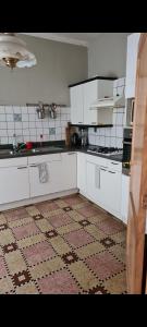 哈勒maison de vacances的厨房配有白色橱柜和瓷砖地板。
