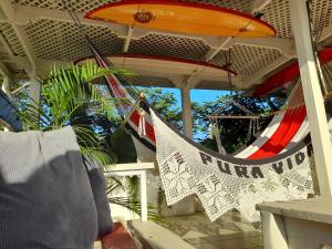 塔马林多Zulu Surf Hotel Tamarindo的一个带冲浪板的门廊上的吊床