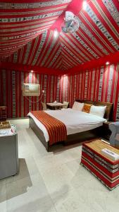 Aflāj巴迪雅沙漠营地酒店的一间卧室设有一张大床和红色的墙壁