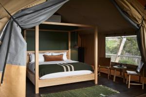 梅顿Metung Hot Springs的一间帐篷内带天蓬床的卧室