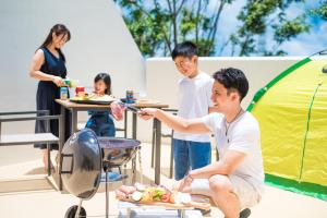 冲绳岛市HiyagunLanaiResort的一群人站在帐篷前的烧烤架上
