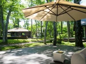 山中湖村Forest Villa Yamanakako的一个带遮阳伞的庭院和一座建筑