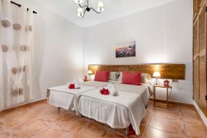 La GuanchaCasa Teresa的一间卧室配有两张带白色床单和红色枕头的床。