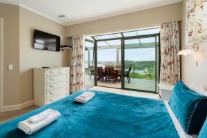 派西亚Swallows Nest - Paihia Holiday Home的一间卧室设有蓝色的床和一个阳台