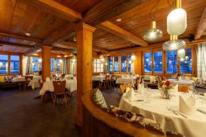 安德马特Sonne Andermatt Swiss Quality Hotel的餐厅设有白色的桌椅和窗户。