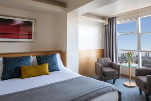 伦敦伦敦圣吉尔斯酒店的配有一张床和一把椅子的酒店客房