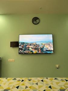 瓦斯科达伽马Studio Apt with Rooftop Panoramic views @ Dabolim的挂在绿色墙上的电视,带时钟