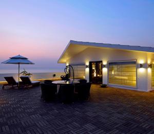 孟买Sun-n-Sand Mumbai Juhu Beach的一座配有桌椅和遮阳伞的建筑