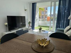 英格兰海滩Sunny Apartment Tanife by Yumbo的客厅配有木桌和电视。