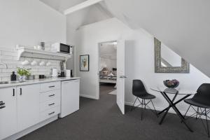邦加里Bella Abode on Bribie - Loft with Pool的白色的厨房配有黑色的椅子和桌子