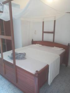 江比阿Iddi House的一间卧室配有一张带白色床单的木床