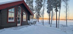 法伦Lakeside log cabin Främby Udde Falun的雪地小屋,配有桌椅