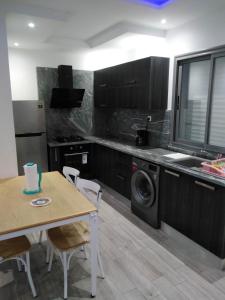 乌姆苏克Résidence Inès Djerba Appartement de Luxe的厨房配有桌子和洗衣机。