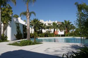 Estepona2152-Modern apt with private beach的一座棕榈树游泳池和一座建筑
