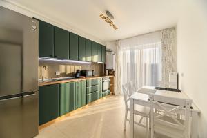 布拉索夫Luxury Landing Apartments Complex Qualis Brasov的厨房配有绿色橱柜和桌椅