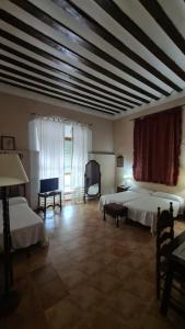 HueteCasa Palacio Conde de Garcinarro的大房间设有两张床和电视
