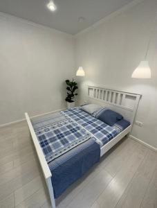 阿斯塔纳Стильная 2-х комнатная ЖК Браво的一间卧室配有一张带蓝色床单和植物的床