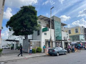 比亚埃尔莫萨Hotel Santo Domingo Express的走在建筑物前的街道上的女人