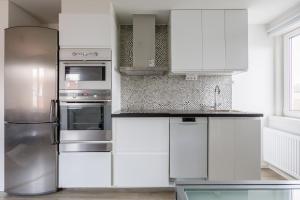 延雪平Flores 3的厨房配有白色橱柜和不锈钢冰箱