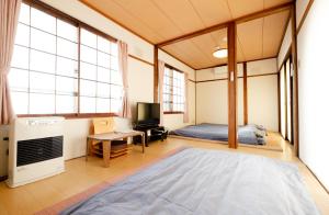 洞爷湖Guest House Matsuyoshi的一间卧室设有一张床、一台电视和窗户。