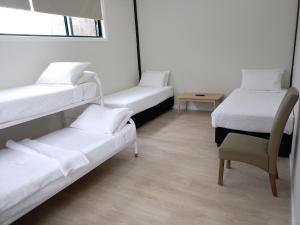 麦夸里港T's Resort & Motel的带三张双层床和椅子的房间