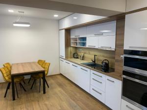 弗林布尔克Wellness & Spa Apartments Lipno - Frymburk的厨房配有白色橱柜和木桌