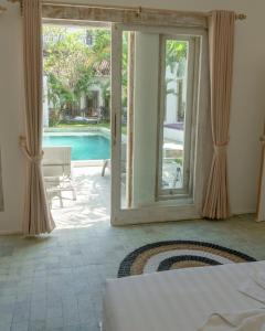 金巴兰Surga Tropical Suites的一间卧室设有通向游泳池的门