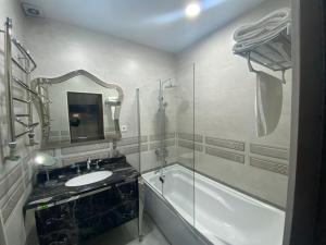 杜尚别Sunrise Apartments的一间带水槽、浴缸和镜子的浴室