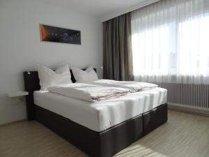 因斯布鲁克Holiday flat, Axams的卧室配有一张带白色床单的大床和窗户。