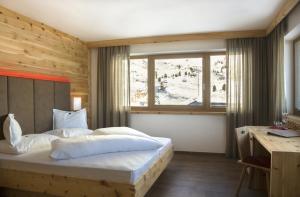 塞尔瓦迪加尔代纳山谷帕苏蝶鞍多洛米蒂山度假村 的一间卧室配有一张床、一张书桌和一个窗户。