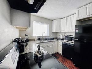 亚特兰大Quiet & Quaint apartment, 5 mins to airport and 15 mins to downtown的厨房配有白色橱柜和黑色冰箱。