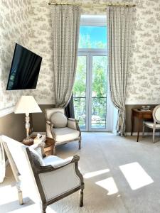 卢瓦尔河畔蒙路易Le Clos du Roc的客厅配有椅子和墙上的电视