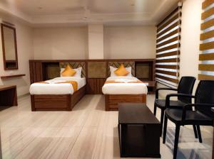钦奈RR Mount Elite Suites的酒店客房带两张床和一张桌子以及椅子。