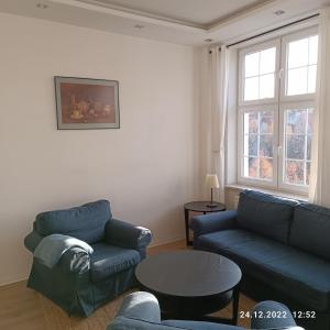 格但斯克Apartament Długa 35的客厅配有2张蓝色的沙发和1张桌子