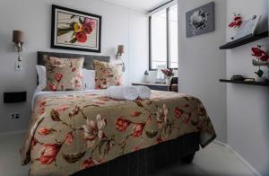 开普敦Flamingo Sea Point Sea View Luxury Best Position 1 Bedroom Apartment Queen Size Bed & Inverter For TV的一间卧室配有一张带花卉床罩的床