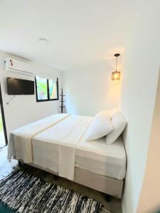 乌巴图巴Yabás Praia的一间白色卧室,配有床和电视