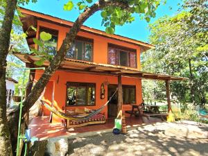 萨玛拉Casa Terra的一座橙色房子前面设有吊床