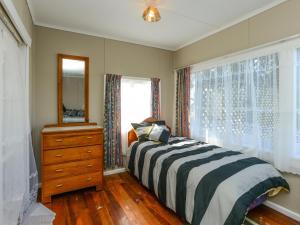 WaimaramaWaipuka - Ocean Beach Holiday Home的一间卧室配有一张床、梳妆台和镜子