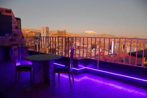 拉巴斯Terraza Hotel的阳台配有一张桌子和椅子,配有紫色灯