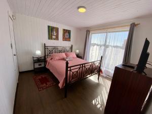 皮奇勒姆Hostal Dolegant Pichilemu 2的一间卧室配有一张带粉色床单的床和一扇窗户。