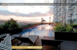 马尼拉Home Sweet Home at Manila Bay的一座带桌椅的游泳池位于酒店大楼旁