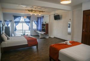 巴卡拉尔Seven Blue House Village & Lodge的酒店客房设有两张床和电视。
