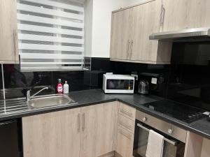 NortholtPark View Serviced Apartment - Next to Northolt Tube Station - Near Central London & Wembley的厨房配有微波炉和水槽